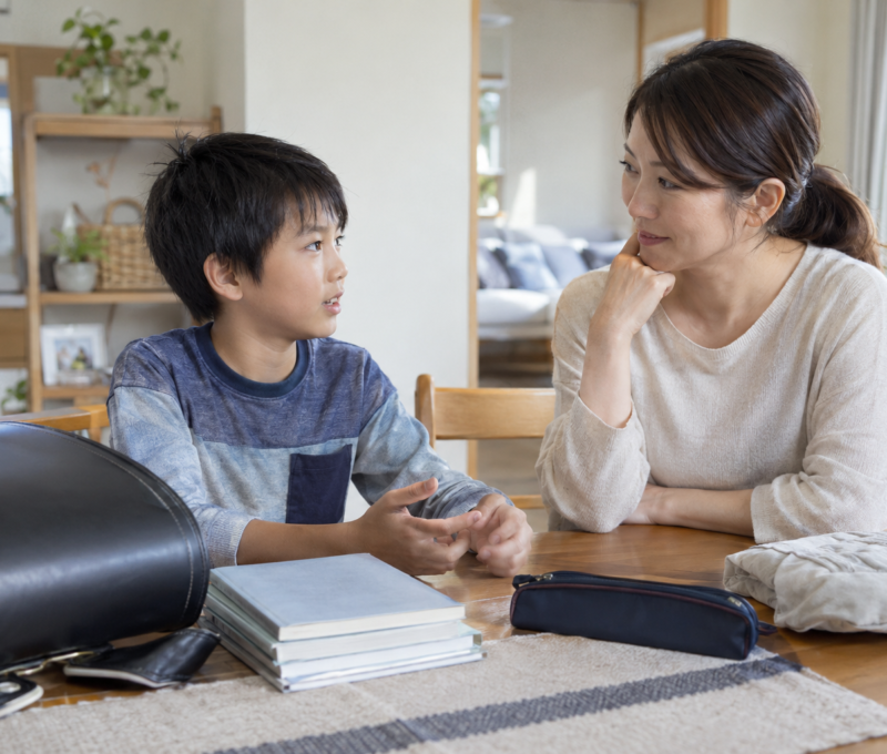 学用品を前に学校生活について相談する日本人の母親と男の子